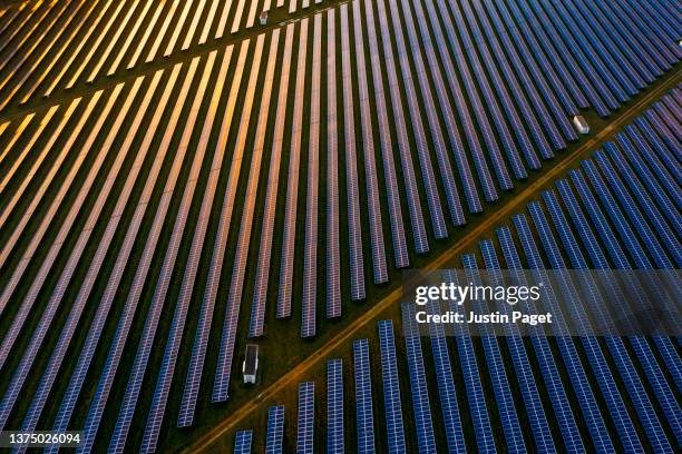 drone view over a field of solar panels at sunset - solar farm stockfoto's en -beelden