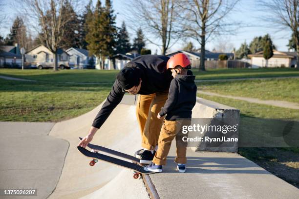 father skateboarding with his son - skateboard park stock pictures, royalty-free photos & images