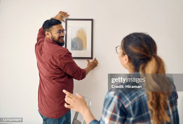 shot of a young couple decorating their house together - hangen stockfoto's en -beelden