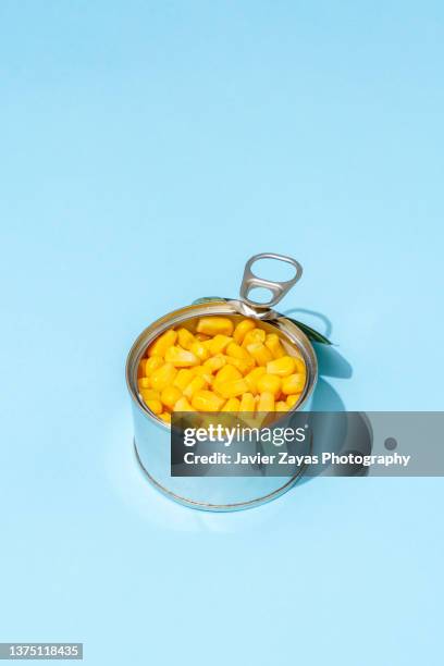 sweetcorn grains in a can on blue background - estaño fotografías e imágenes de stock