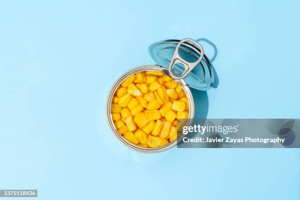 sweetcorn grains in a can on blue background - blechdose stock-fotos und bilder