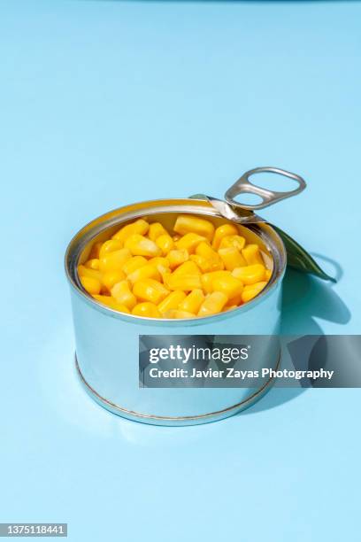 sweetcorn grains in a can on blue background - estaño fotografías e imágenes de stock