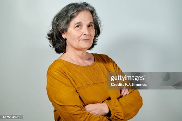 portrait of mature woman with crossed arms on white background - portrait casual woman background studio stockfoto's en -beelden