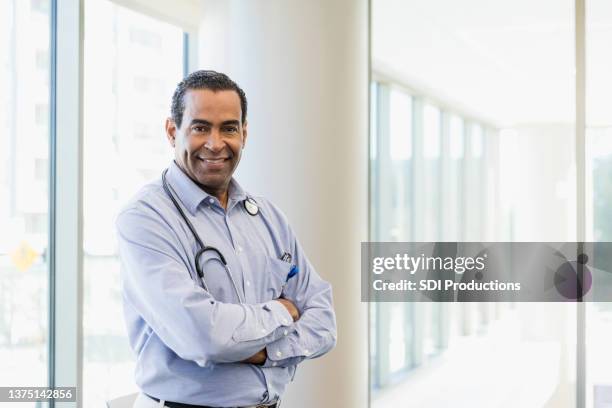 confident, mature adult male doctor smiles for portrait - businesswear stock pictures, royalty-free photos & images