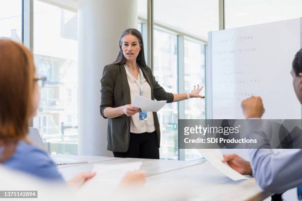 female hospital administrator uses whiteboard during staff meeting - doctor presentation stock pictures, royalty-free photos & images