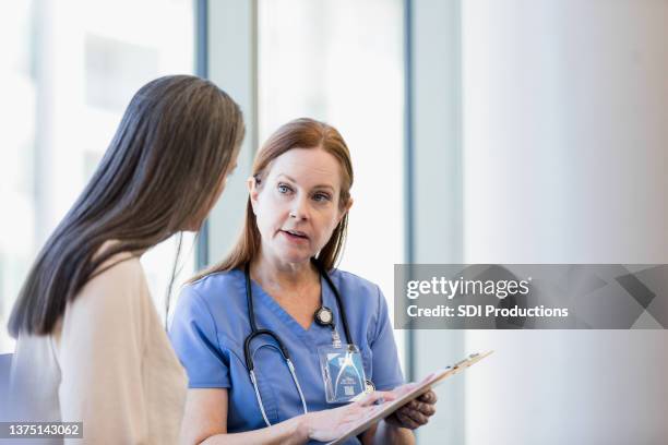 mature female doctor discusses test results with female patient - female patient stock pictures, royalty-free photos & images