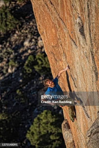 male rock climber on vertical granite rock wall and holding his rope - clambering imagens e fotografias de stock