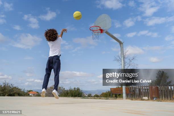 back shot of a boy shooting the basketball into the basket - basketball shot stock pictures, royalty-free photos & images