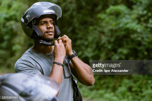 biker putting on helmet in nature park - sports helmet stock pictures, royalty-free photos & images