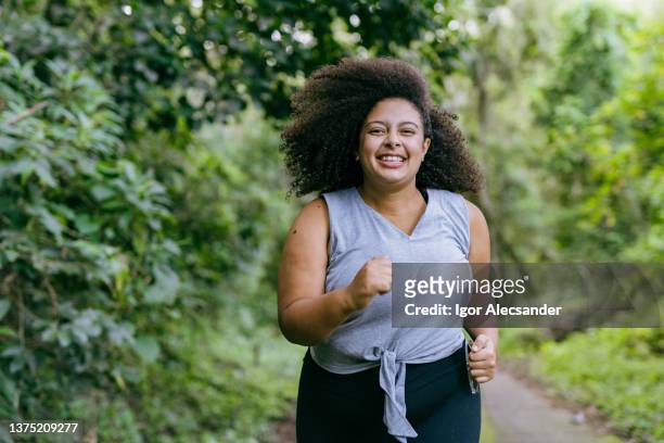 plus size woman running in the natural park - fat imagens e fotografias de stock