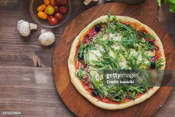 freshly baked homemade prosciutto and arugula pizza with olives and mozzarella cheese - pizza directly above stock pictures, royalty-free photos & images