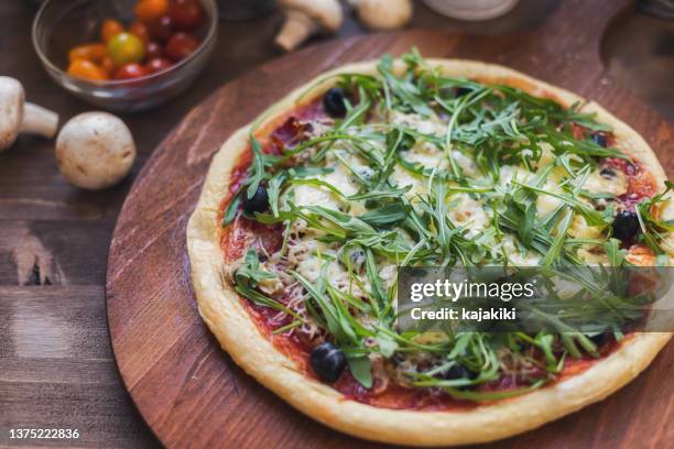 freshly baked homemade prosciutto and arugula pizza with olives and mozzarella cheese - arugula stock pictures, royalty-free photos & images