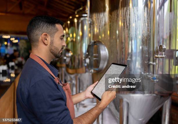 mann, der in einer brauerei arbeitet und die produktionslinie kontrolliert - tablet alcohol stock-fotos und bilder