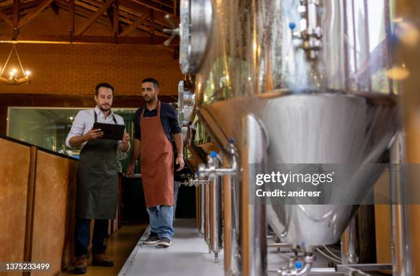 team of men working at a brewery and controlling the production line - bier brouwen stockfoto's en -beelden