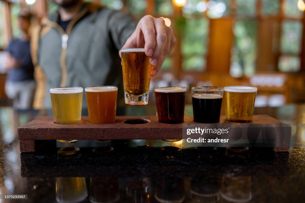 醸造所でサンプラーからビールを試している男のクローズアップ