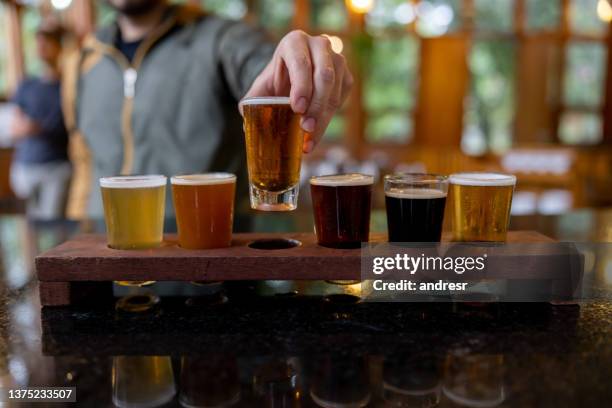 close-up on a man trying beers from a sampler at a brewery - 嘗 個照片及圖片檔