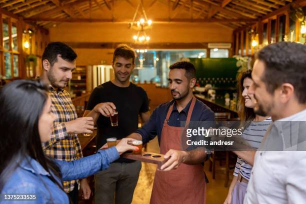 group of people drinking samples of beer after taking a tour at a brewery - proeven stockfoto's en -beelden