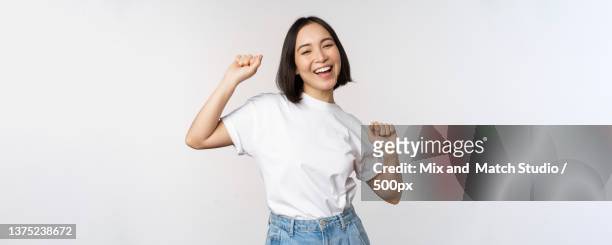 happy dancing korean girl posing against white background,wearing - blank t shirt model stock pictures, royalty-free photos & images