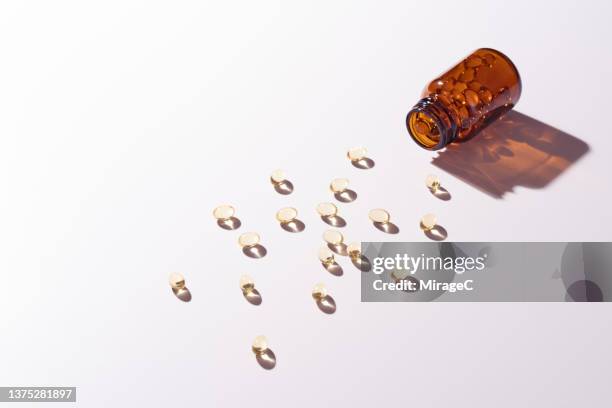 soft capsules of nutritional supplement spilled from a glass pill bottle - fish oil foto e immagini stock