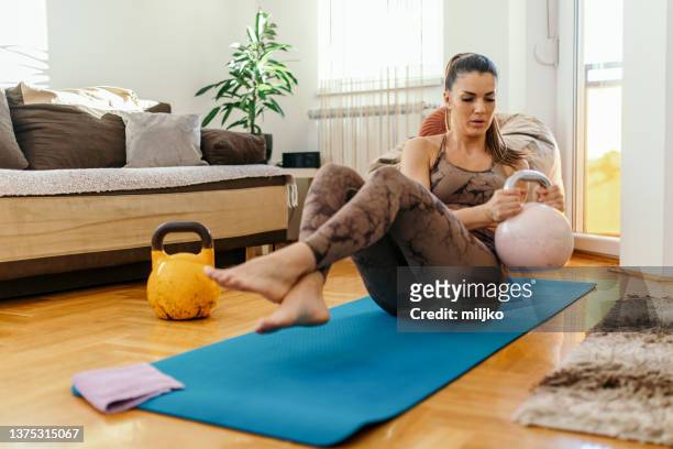 woman doing fitness exercise at home - kettle bells stockfoto's en -beelden