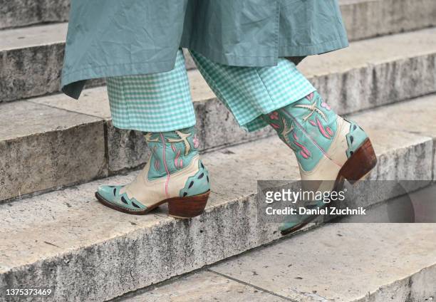 Guest is seen wearing a teal and white cowboy boots outside the Nanushka show during Paris Fashion Week A/W 2022 on March 01, 2022 in Paris, France.