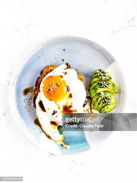 toast with fired egg and avocado on a plate - avocado toast white background stockfoto's en -beelden