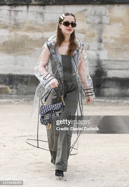 Guest is seen wearing a clear coat, green top and green pants with a Dior bag outside the Dior show during Paris Fashion Week A/W 2022 on March 01,...