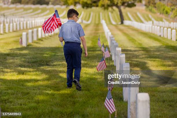 young boy placing flags on veterans grave - military grave stock pictures, royalty-free photos & images