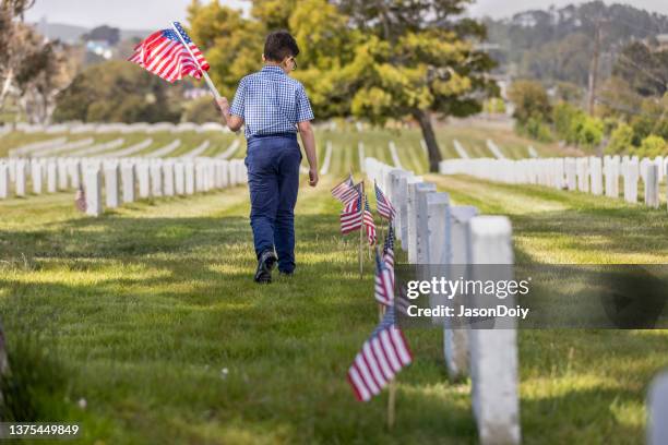 young boy placing flags on veterans grave - memorial day flag ceremony stock pictures, royalty-free photos & images