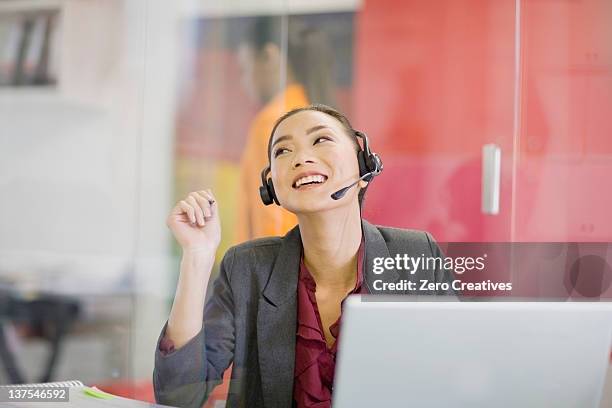 businesswoman on headset at desk - filipino woman smiling stock pictures, royalty-free photos & images