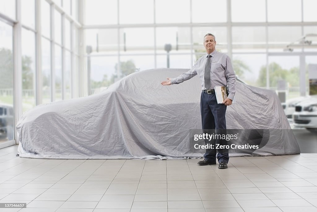 Car salesman displaying car under cloth