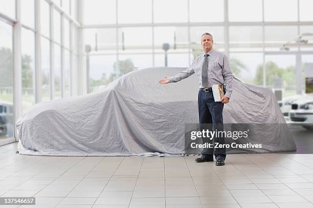 car salesman displaying car under cloth - car salesman stock pictures, royalty-free photos & images