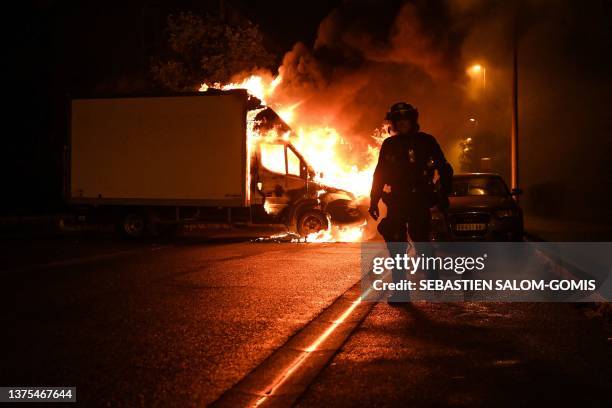 French anti riot police officer walk past a burning truck in Nantes, western France on early July 1 four days after a 17-year-old man was killed by...