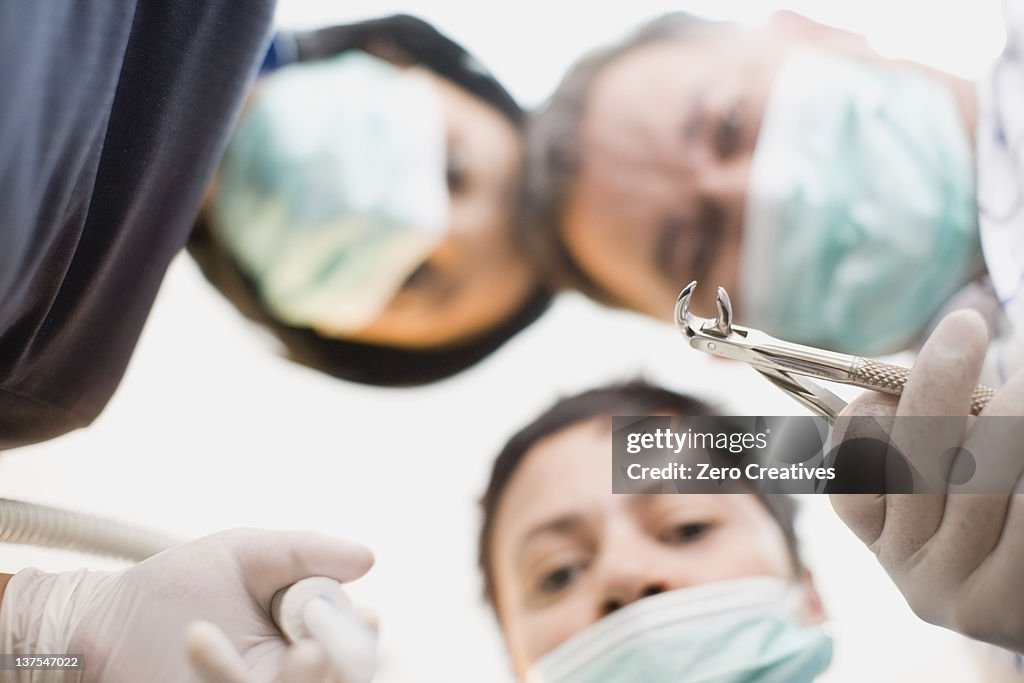 Dentists with tool peering over patient