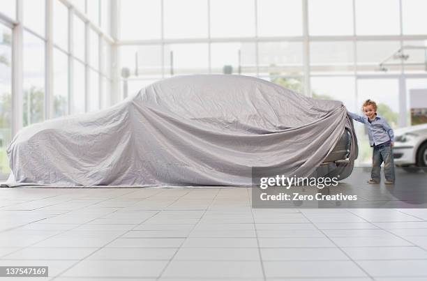 girl peeking under cloth on car - dekzeil stockfoto's en -beelden