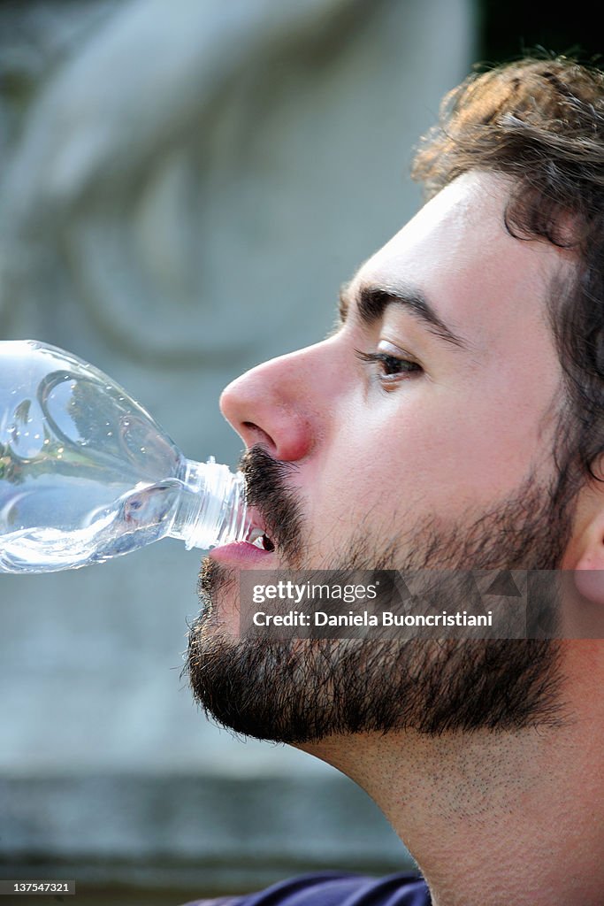 Man drinking from water bottle outdoors