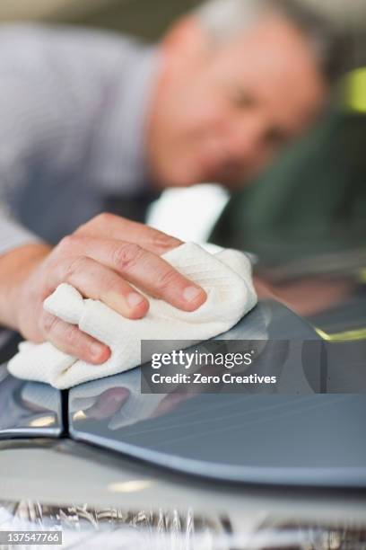 salesman shining car in showroom - clean car dealership stock pictures, royalty-free photos & images