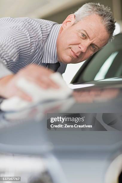 salesman shining car in showroom - clean car dealership stock pictures, royalty-free photos & images