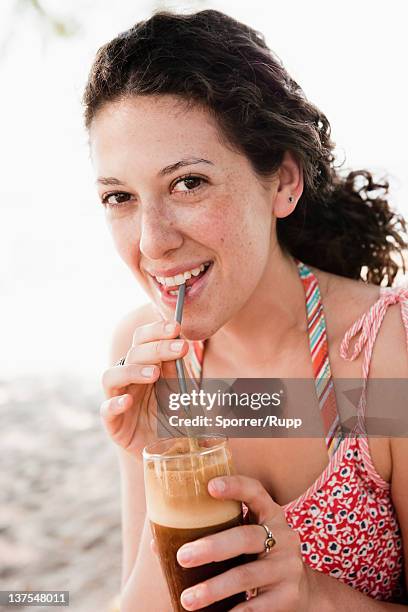 smiling woman drinking through straw - coffee drink - fotografias e filmes do acervo