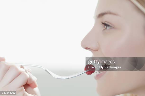 smiling woman eating raspberry - mouth open profile stock pictures, royalty-free photos & images