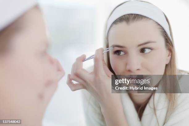 smiling woman plucking her eyebrows - tweezing eyebrows stock pictures, royalty-free photos & images