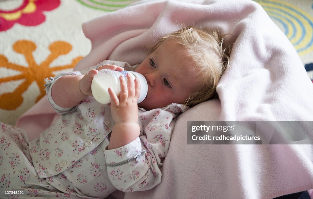 Kleinkind in Decke trinkt aus Flasche