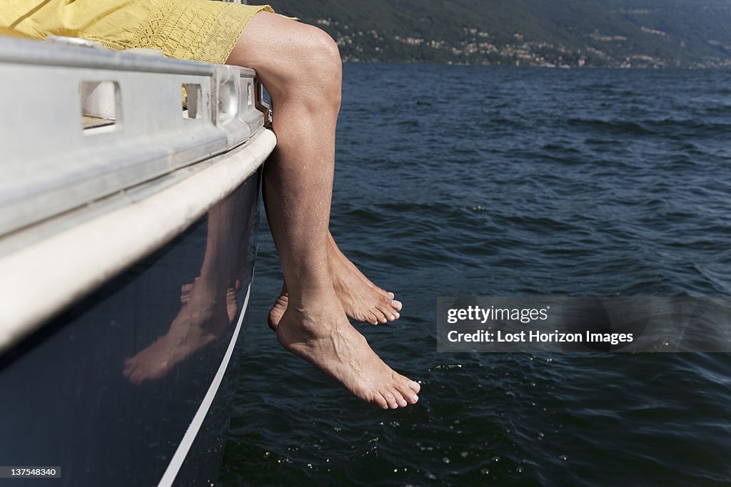 Woman dangling feet from sailboat