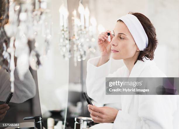 woman in bathrobe applying makeup - applying mascara stock pictures, royalty-free photos & images