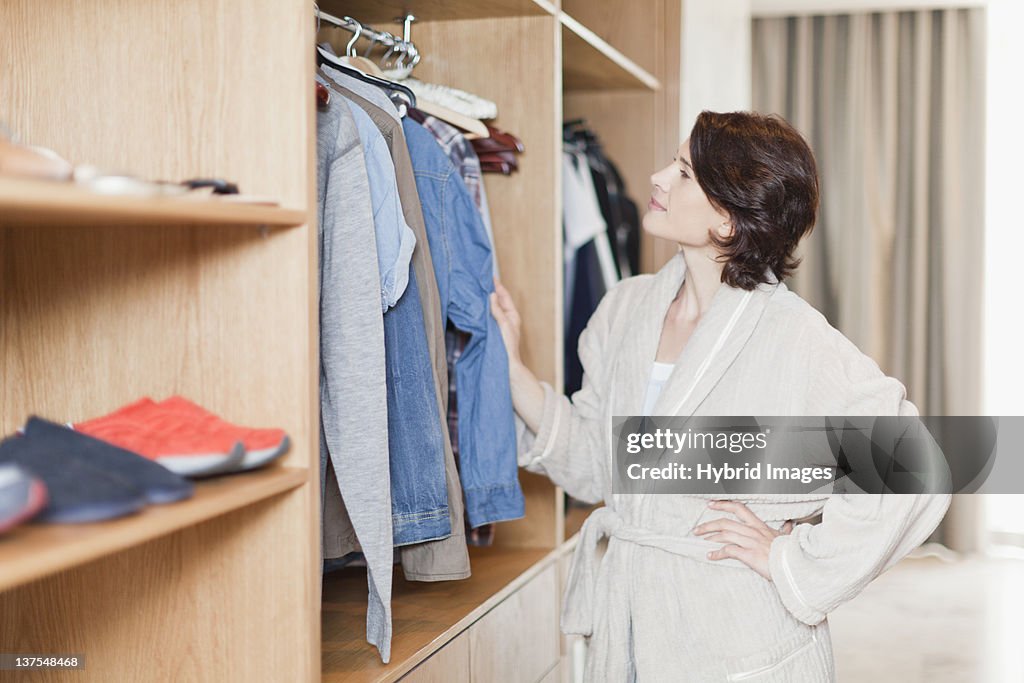 Woman picking clothes out of closet