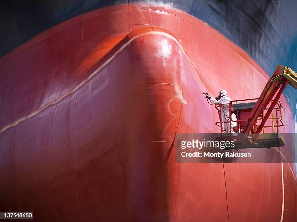 spray painting underside of ship in dry dock - industrial ship fotografías e imágenes de stock