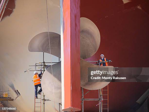 workers checking underside of ship in dry dock - anlegestelle stock-fotos und bilder