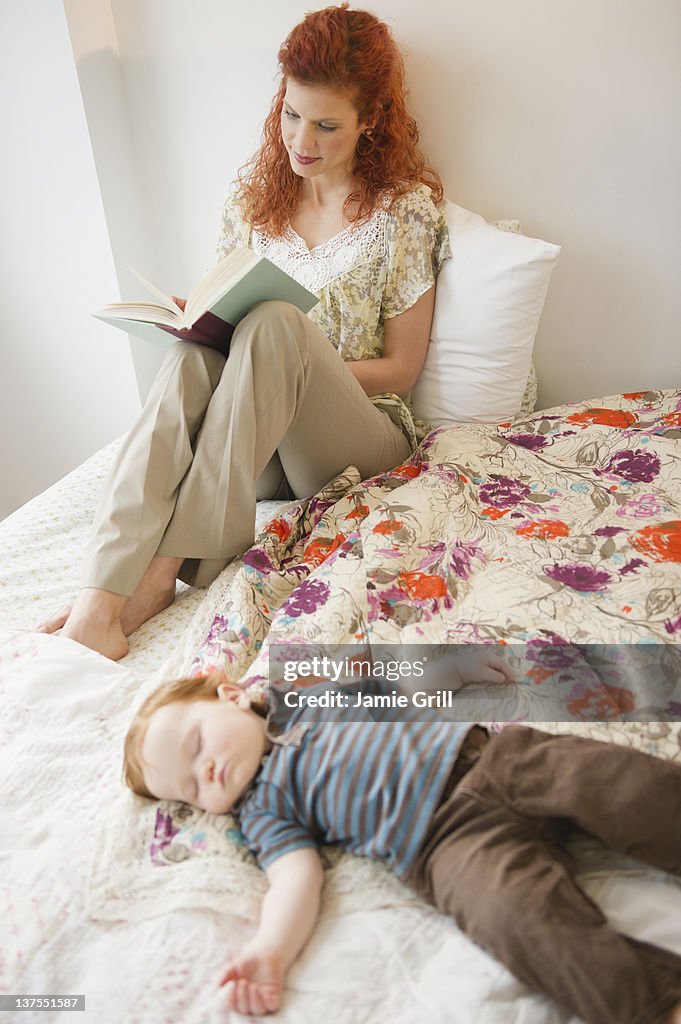 Mother reading book while baby sleeps