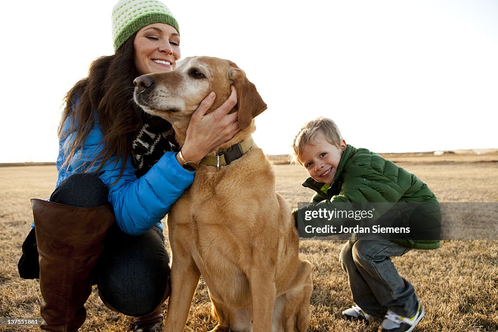 Mom and young son petting their dog.