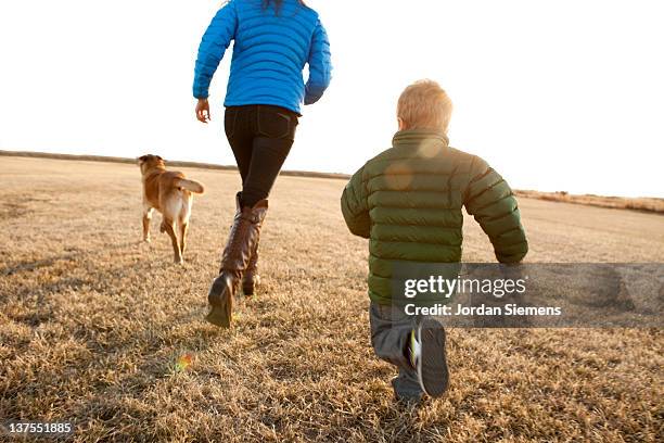 mom and young boy running with their dog. - family children dog fotografías e imágenes de stock